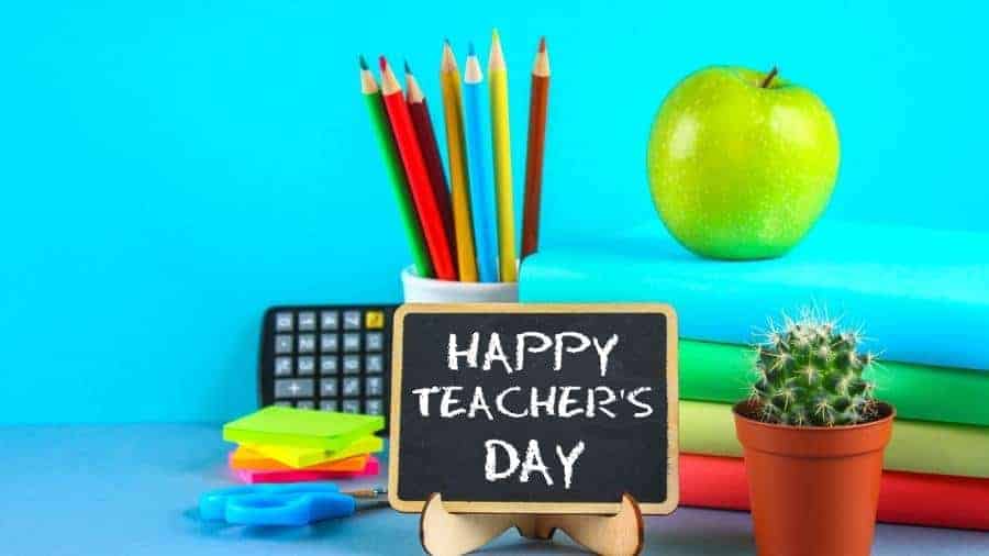 The surface of a teacher's desk with a sign that says "Happy Teacher's Day." 