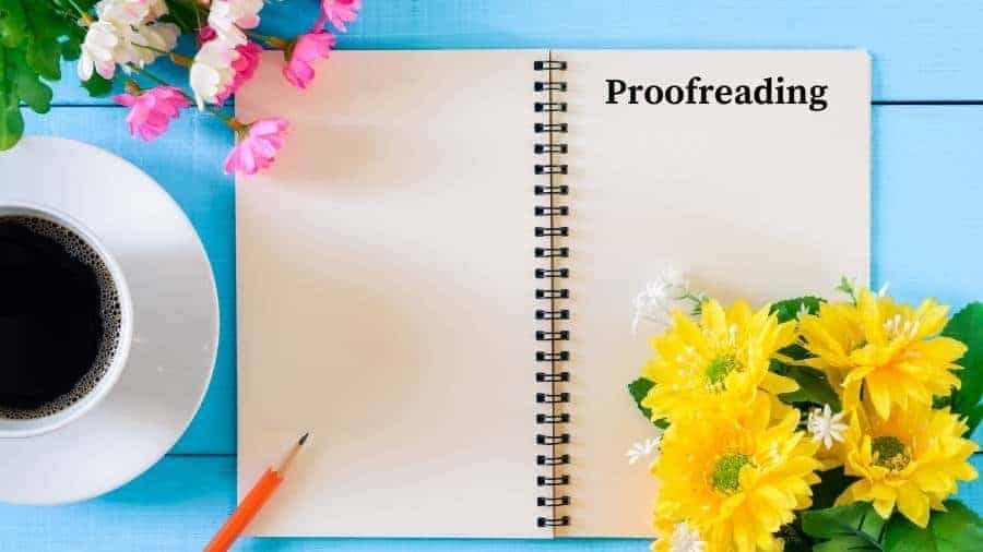 A notebook labeled "Proofreading," a pencil, flowers, and a cup of black coffee lying on a blue bench. 