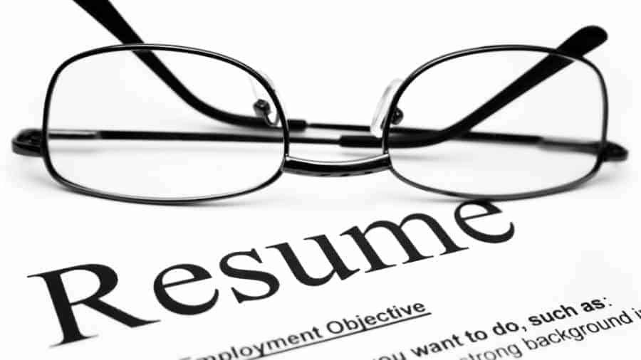 Pair of glasses lying upside down on a résumé.