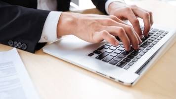 A businessperson typing on a laptop computer. 