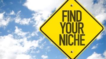 A yellow, diamond-shaped street sign with the message "Find Your Niche." 