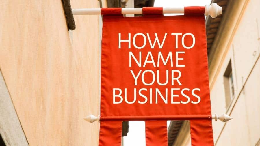 A banner hanging from a wall outdoors displays the message "How to Name Your Business." 