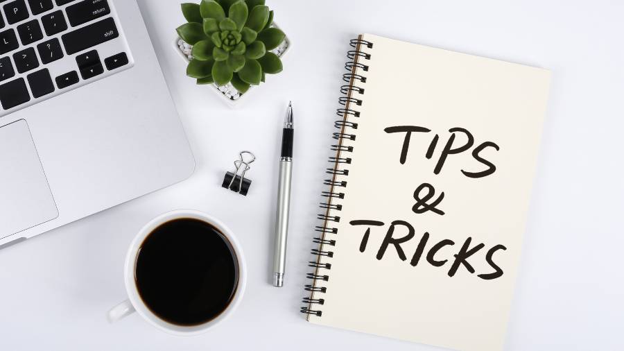 A desk with assorted objects, including a notebook with the words "Tips and Tricks" written on a page. 